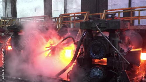 Steel production in the workshop. Heavy industry. Metallurgy factory. Red hot steel metal billets after molten steel casting. Hot metal sheet slides along the conveyor. Hot steel bars on the conveyor. photo