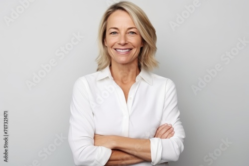 Portrait of happy mature businesswoman with arms crossed against grey background