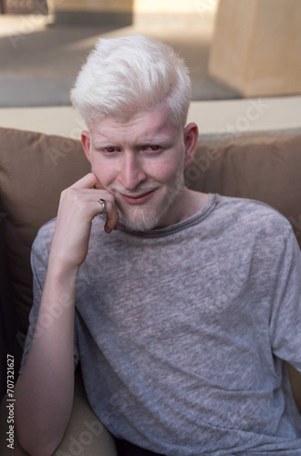 Portrait of a young albino man sitting down