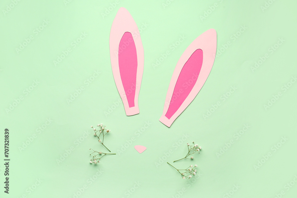 Paper bunny ears and gypsophila flowers on green background