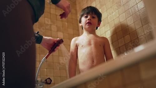Mother washing child's body during night time routine before bed. Parenting ritual of bathing little reluctant boy son