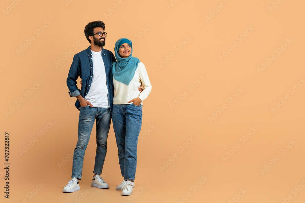 Stylish arab muslim couple in trendy clothes standing confidently and looking away Stylish arab muslim couple in trendy clothes standing confidently and looking away