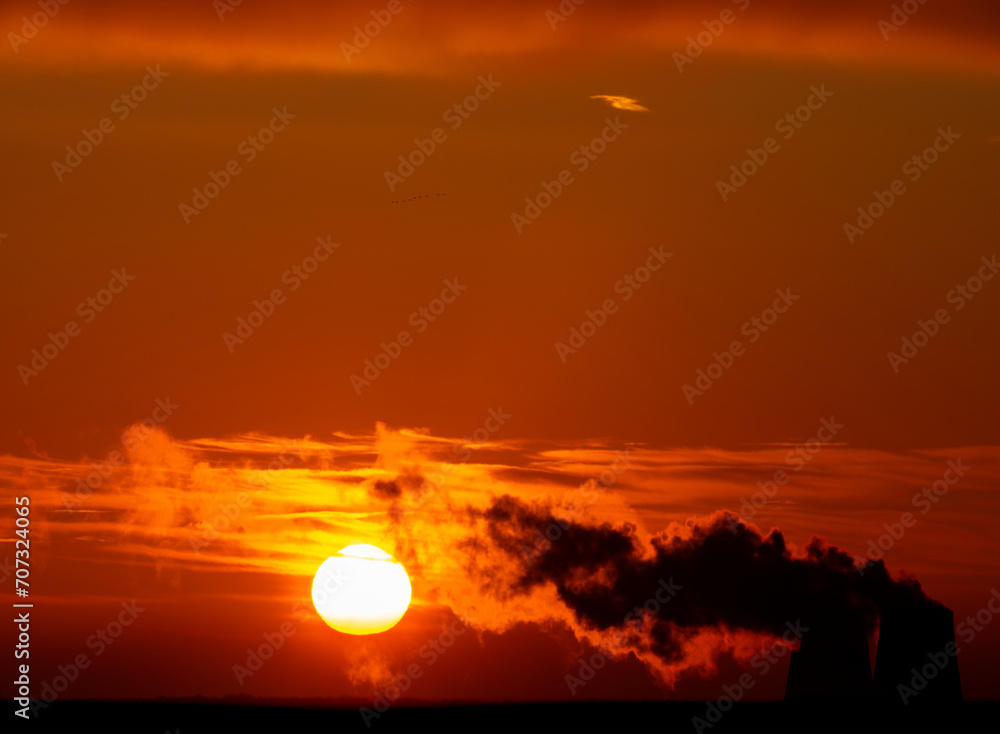 Dramatic black smoke with orange dawn sky with the rising sun.