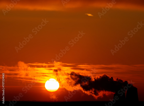 Dramatic black smoke with orange dawn sky with the rising sun.