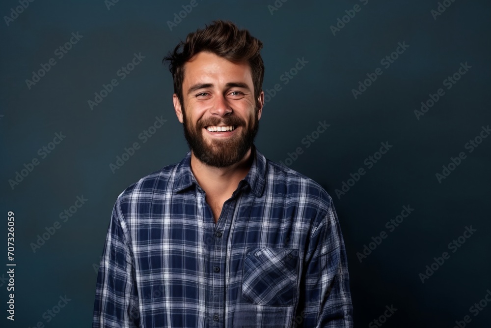Portrait of a handsome young man in checkered shirt on blue background.