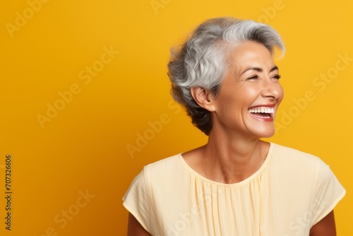 Happy smiling senior woman with grey hair. Isolated on orange background