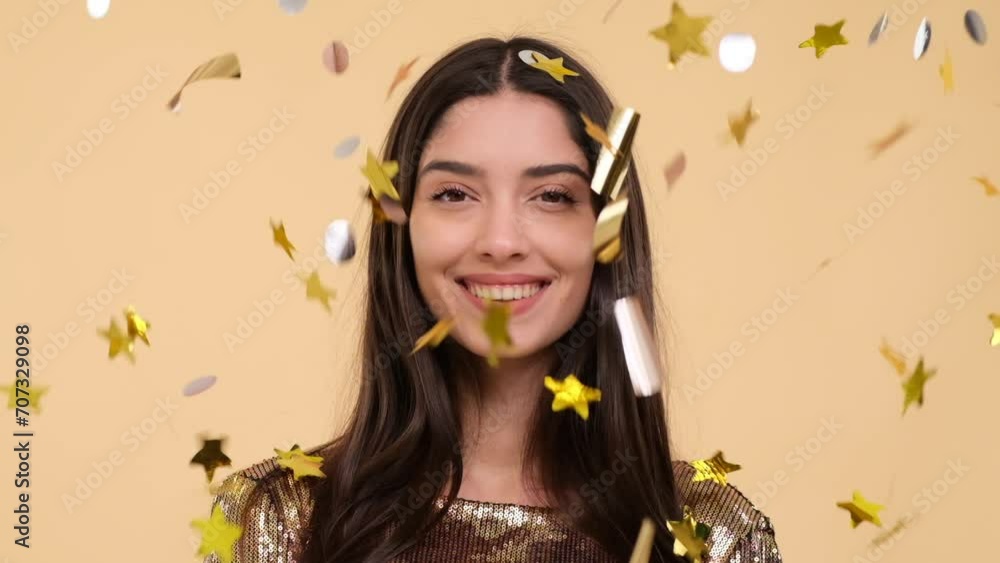 Smiling Caucasian woman radiates joy in a portrait set against a warm beige background, surrounded by cascading confetti that adds a festive touch to the scene, capturing a moment of pure happiness. Smiling Caucasian woman radiates joy in a portrait set against a warm beige background, surrounded by cascading confetti that adds a festive touch to the scene, capturing a moment of pure happiness.