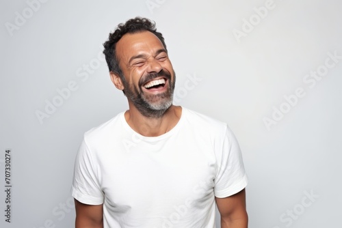 Portrait of a happy middle-aged man laughing against grey background