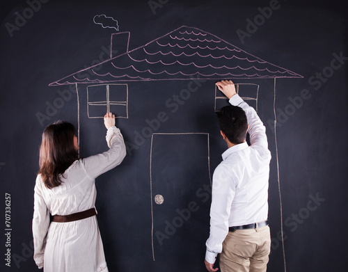 a man and woman standing in front of a chalk drawing of a house photo