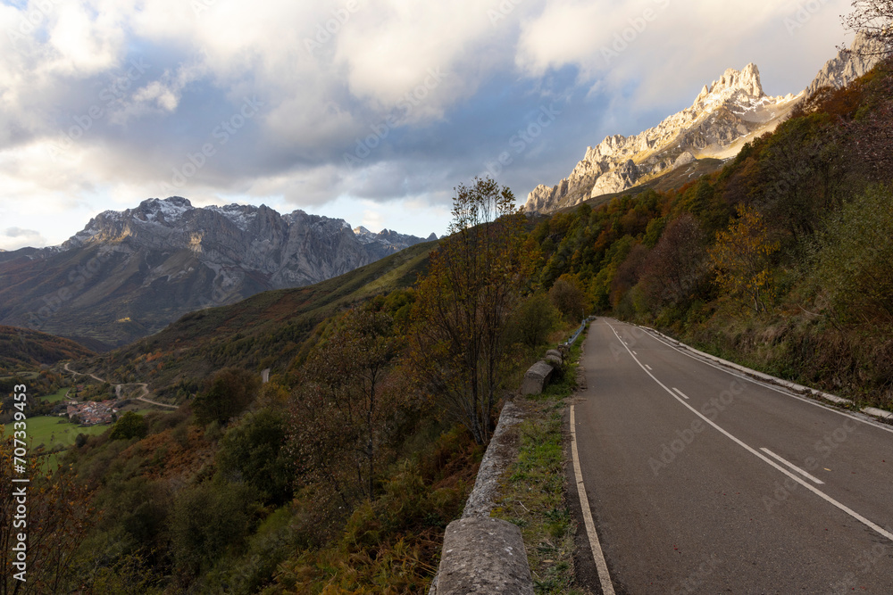 Landscape of Picos de Europa national park road through autumn forest with bright colorful leaves and sunset Landscape of Picos de Europa national park road through autumn forest with bright colorful leaves and sunset