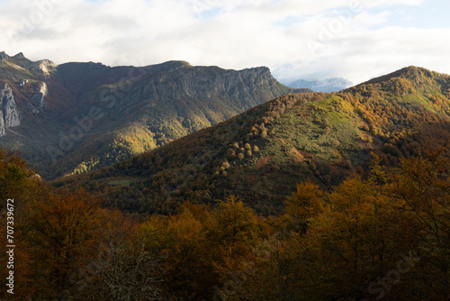 Picos de Europa national park at sunset. Panoramic view of mountain range at sunset with bright leaves and colorful yellow and orange