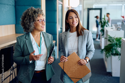 Foto Happy CEO and her younger colleague talking in office.