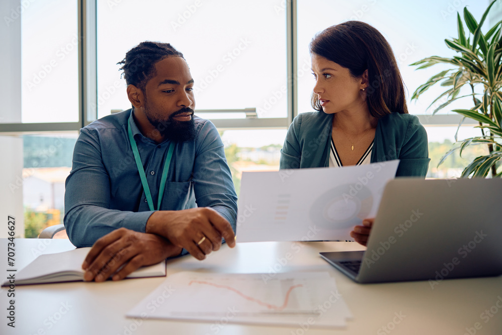 Black entrepreneur and his female colleague analyzing business reports on meeting in office. Black entrepreneur and his female colleague analyzing business reports on meeting in office.