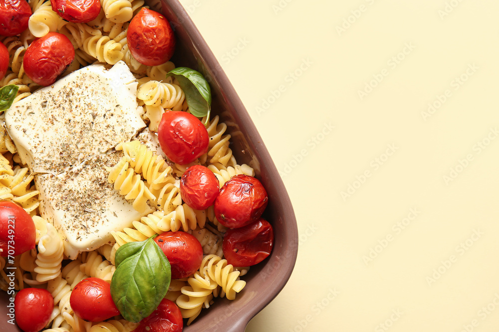Baking dish of tasty pasta with tomatoes and feta cheese on yellow background Baking dish of tasty pasta with tomatoes and feta cheese on yellow background