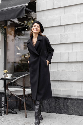 beautiful woman with beret outside in front of cafe. parisian style,portrait of cute girl female in black coat.