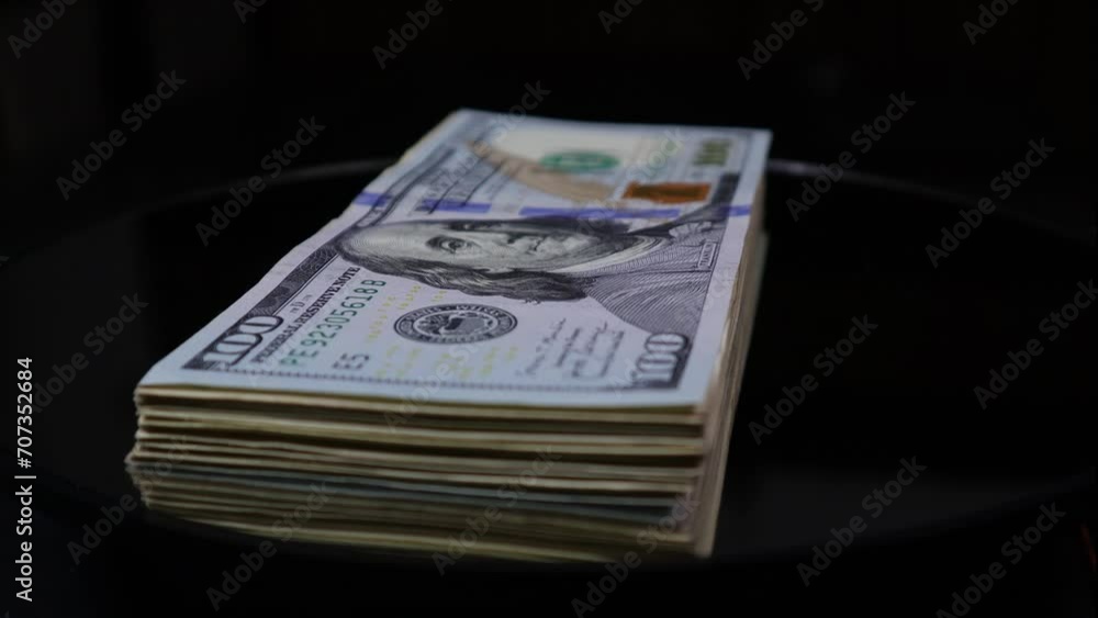 The US dollar bills stack rotating on an automatic table and creating reflection on glass plate The US dollar bills stack rotating on an automatic table and creating reflection on glass plate