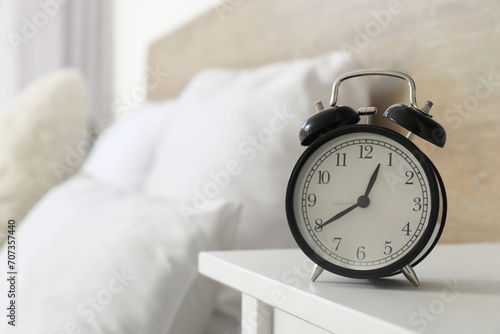 Alarm clock on bedside table in bedroom, closeup photo