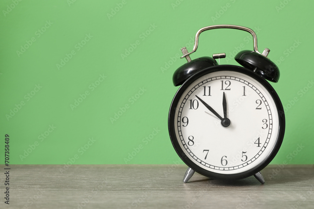 Alarm clock on table near green wall, closeup Alarm clock on table near green wall, closeup
