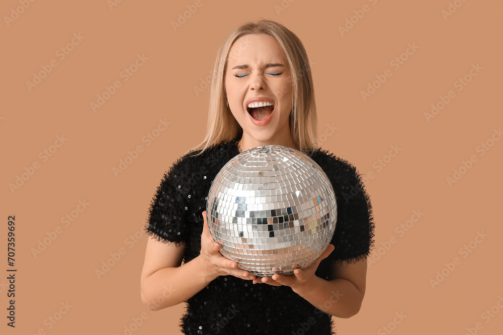Beautiful young woman with disco ball screaming on brown background Beautiful young woman with disco ball screaming on brown background
