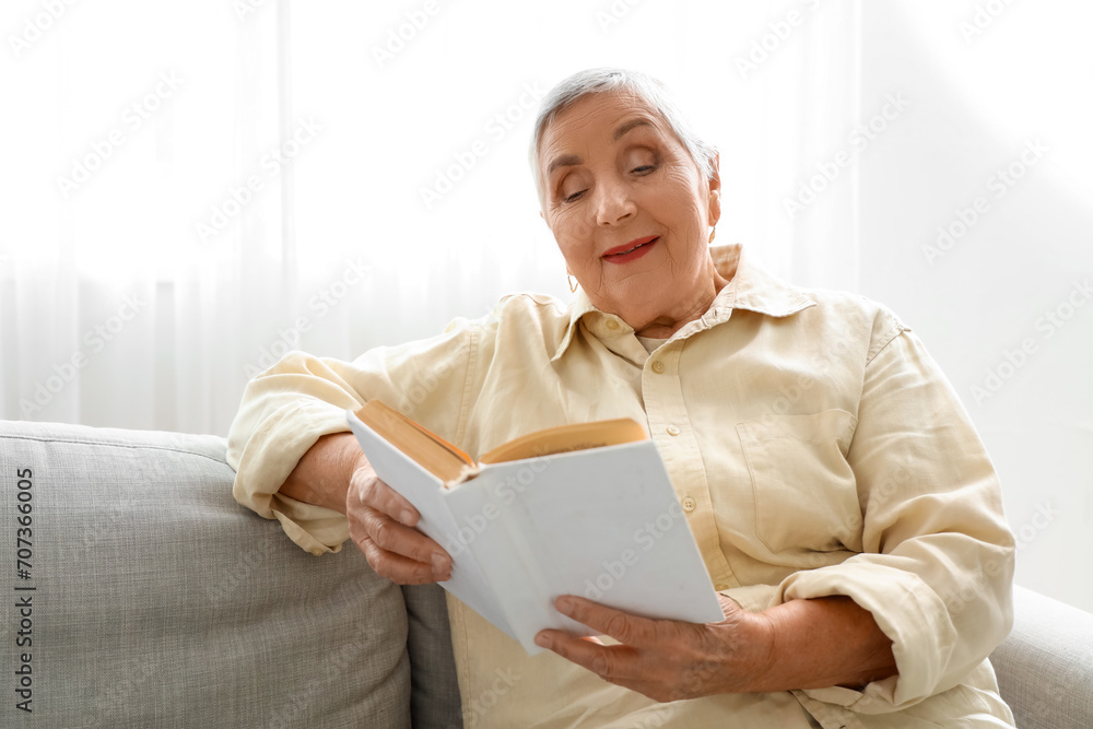 Senior woman reading book on sofa at home Senior woman reading book on sofa at home