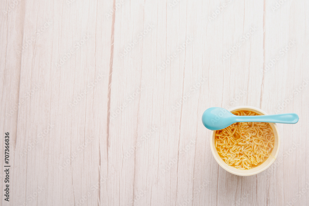 Overhead view of a bowl of instant pasta soup with a spoon light blue on white background. Lunch. Fast food concept Overhead view of a bowl of instant pasta soup with a spoon light blue on white background. Lunch. Fast food concept