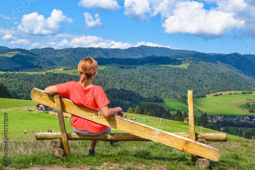 Woman sitting on a bench near the Homole Cable Car station. A viewpoint from which you can admire the panorama of the Beskid Sadecki, Pieniny Mountains, Jaworki (near Szczawnica), Poland. photo