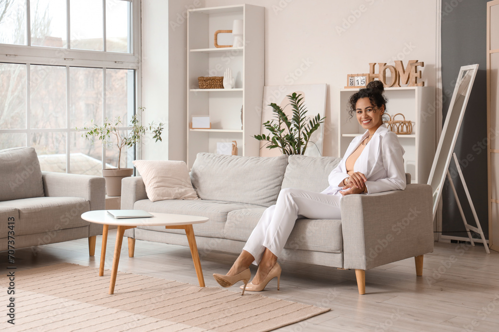 Young African-American businesswoman sitting on sofa at home Young African-American businesswoman sitting on sofa at home