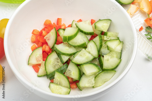 Bowl with pieces of sweet pepper and cucumber for preparing salad.