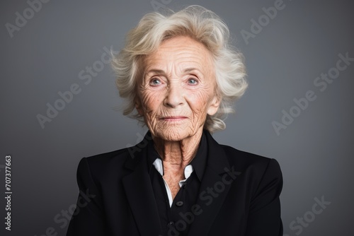 Portrait of an elderly woman in a black suit on a gray background