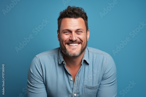 Portrait of a happy casual man laughing and looking at camera over blue background