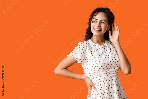 Beautiful young African-American woman on orange background. International Women s Day