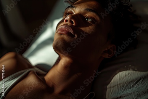 Capturing the vulnerability of the human experience, a portrait of a man laying in contemplation with a furrowed brow, exposed throat and chest, and gentle curve of his lips