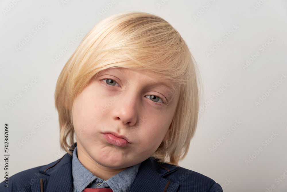 Φωτογραφία Close up portrait of a sad little boy with blond hair on a gray background