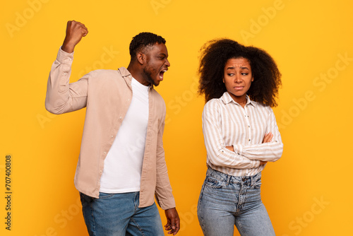 Angry black man yelling, woman upset on yellow backdrop photo