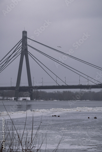 Kyiv, Ukraine - January 11, 2024. Outside, the temperature is sub-zero and frosty. A beautiful bridge can be seen behind. Light snow falls and sprinkles the city.