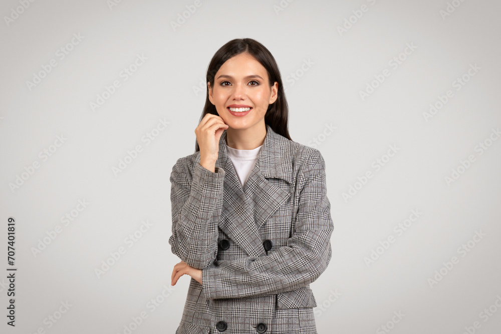 Confident businesswoman smiling, hand on chin, thoughtful pose Confident businesswoman smiling, hand on chin, thoughtful pose