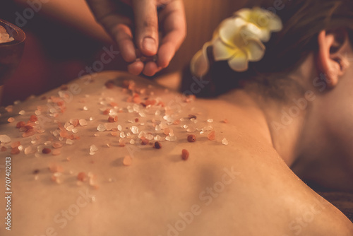 Closeup woman customer having exfoliation treatment in luxury spa salon with warmth candle light ambient. Salt scrub beauty treatment in Health spa body scrub. Quiescent photo