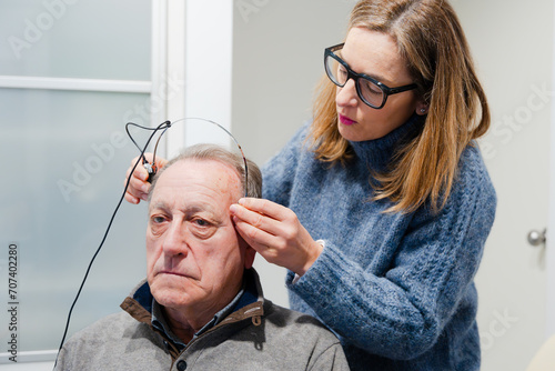Audiologist putting bone headband to patient to check hearing loss photo