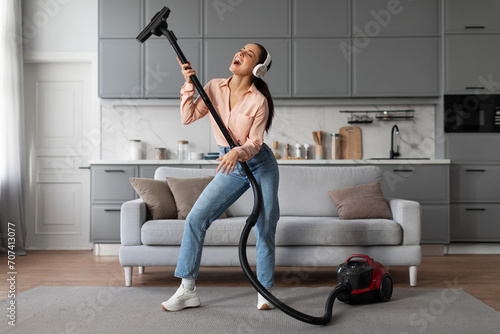 Joyful woman using vacuum cleaner as a mic for fun