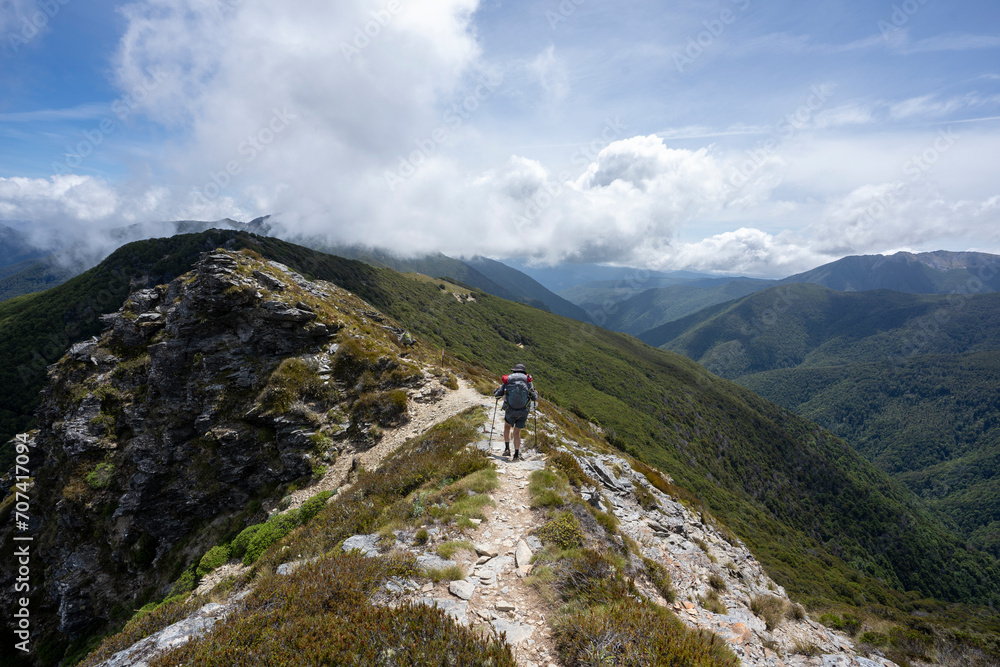 Hiking in the mountains of New Zealand featuring scenic landscape, blue sky and clouds