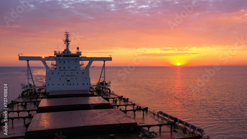 Bulk carrier loaded with grains underway under a crimson sky. Merchant ship Fakarava designed to transport coal, sand or timber. Elegant red ship gliding gently against sun on Black Sea - Jun 21, 2020 photo