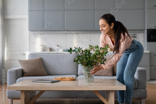 Woman arranging plant on table in living room photo