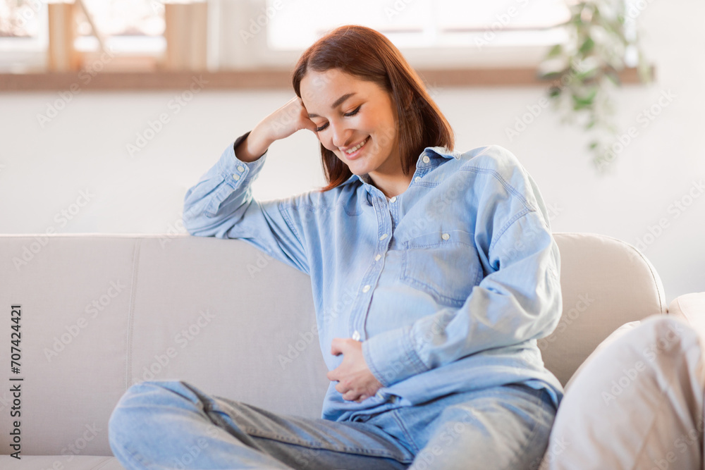 Smiling pregnant woman in casual resting on sofa at home Smiling pregnant woman in casual resting on sofa at home