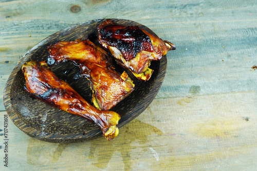 A close up photo of a halved and grilled chicken on a rustic wooden platter