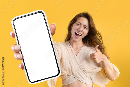 Glad young caucasian lady showing phone with white screen © Prostock-studio