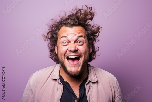 Portrait of a funny young man with curly hair on a purple background © Inigo