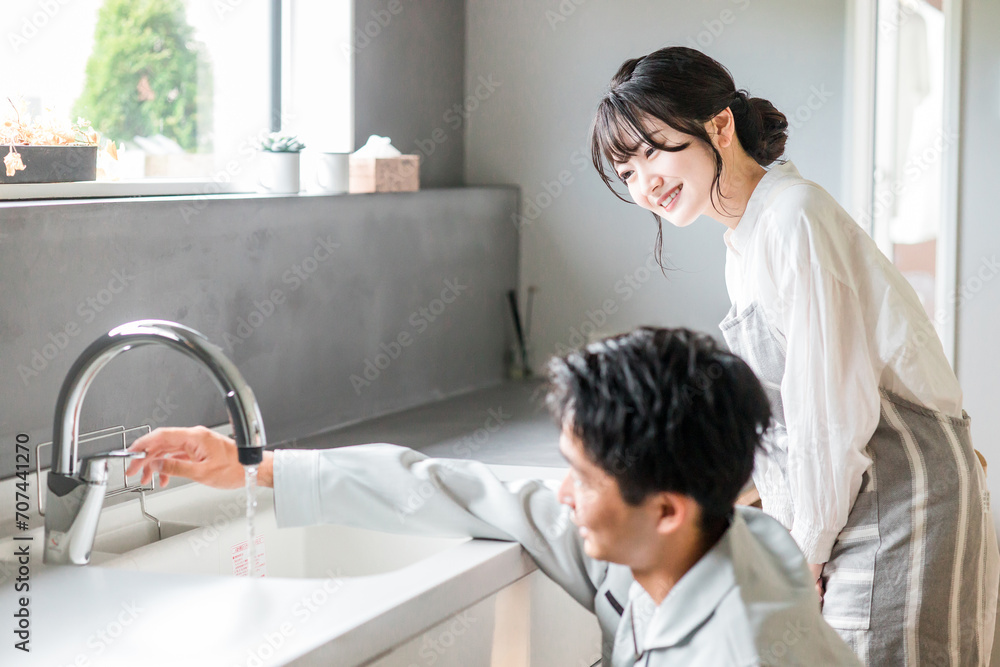 Φωτογραφία キッチンで水道屋・設備屋の説明を受ける主婦の女性