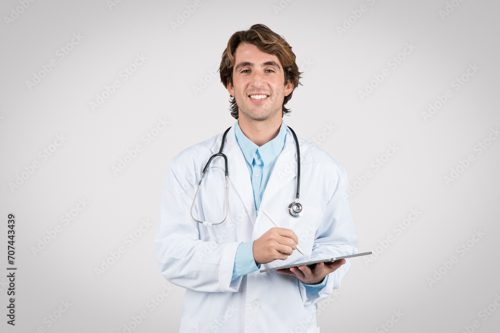 Happy doctor holding tablet wearing stethoscope and smiling Happy doctor holding tablet wearing stethoscope and smiling