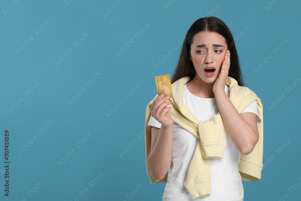 Shocked woman with credit card on light blue background, space for text. Debt problem Shocked woman with credit card on light blue background, space for text. Debt problem