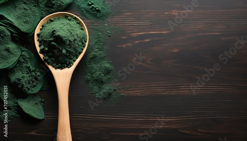 Top view of green spirulina powder on a dark wooden table, a natural supplement for immunity and health, known for lowering cholesterol and blood pressure